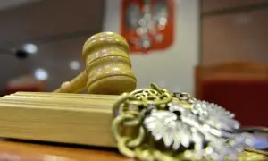 Młotek sędziowski i łańcuch z orłem na tle godła Polski.