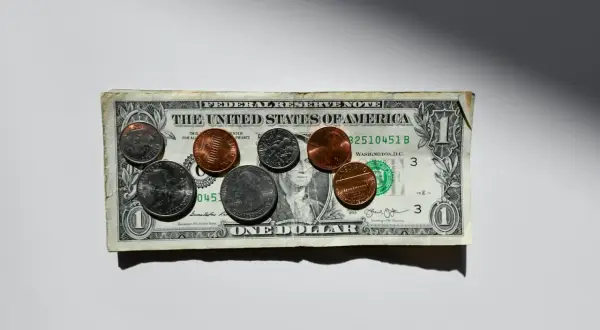 Dolar amerykański z monetami na białym tle.